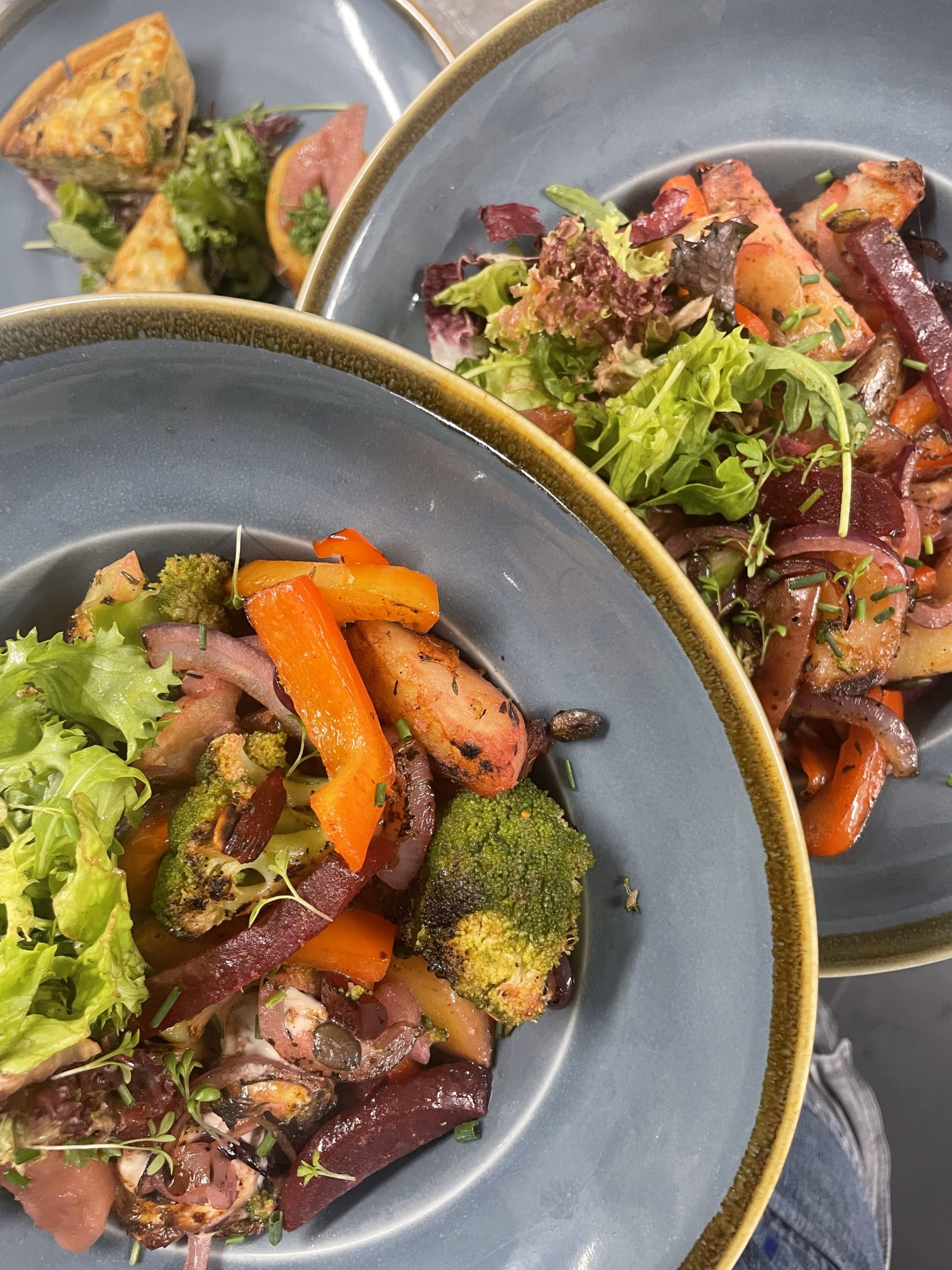 Bord met kleurrijke salade van geroosterde groenten zoals wortel, biet en broccoli, geserveerd met verse sla.