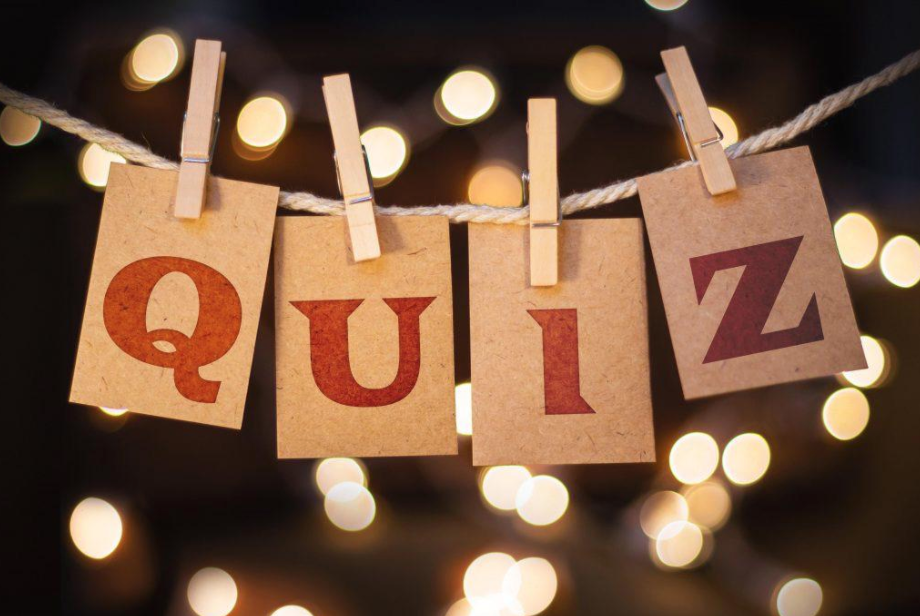 Kraftpapieren kaartjes met de letters Q-U-I-Z aan een touwtje met wasknijpers, op een achtergrond van warme lichtjes