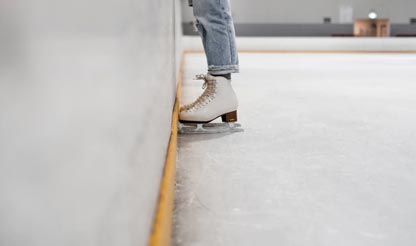 Schaatspret in Thialf Persoon op kunstschaatsen bij de rand van een ijsbaan